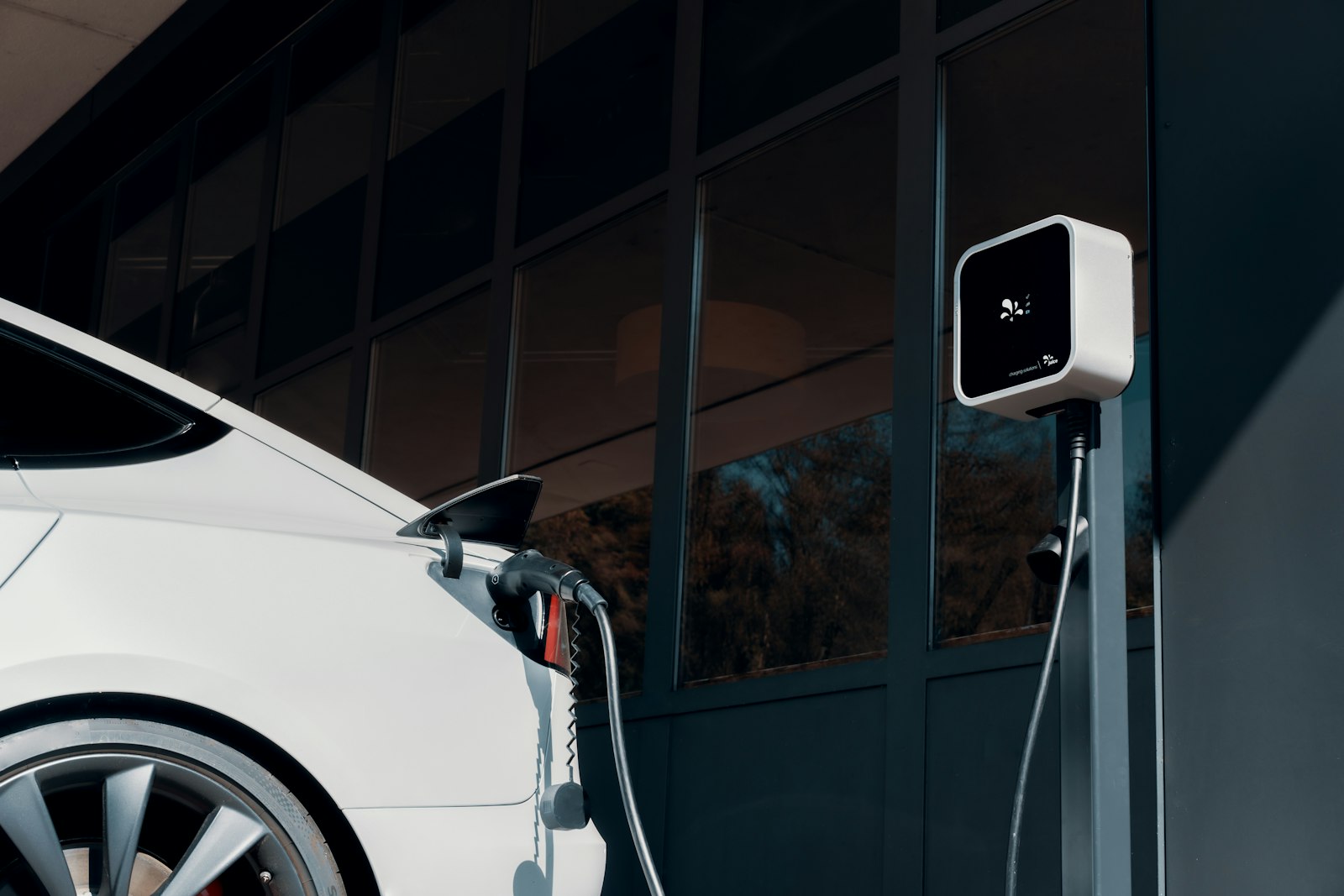 Auto eléctrico blanco cargando en una estación de pared